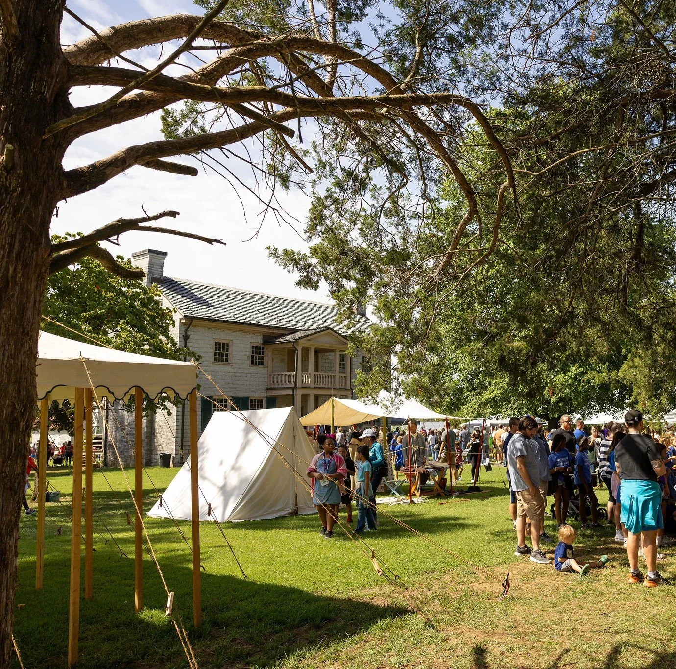 Visitors gathered on the lawn near tents during a living history festival at Historic Rock Castle.